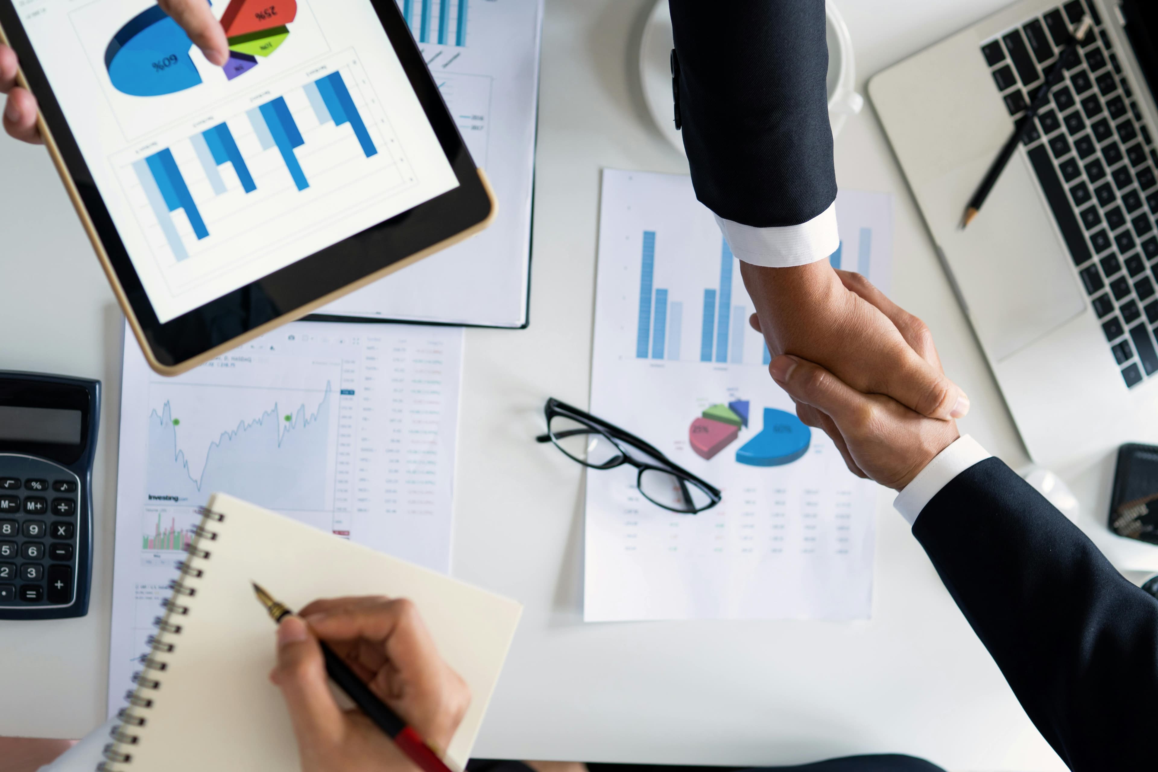 Acuerdo empresarial con reportes y datos sobre la mesa